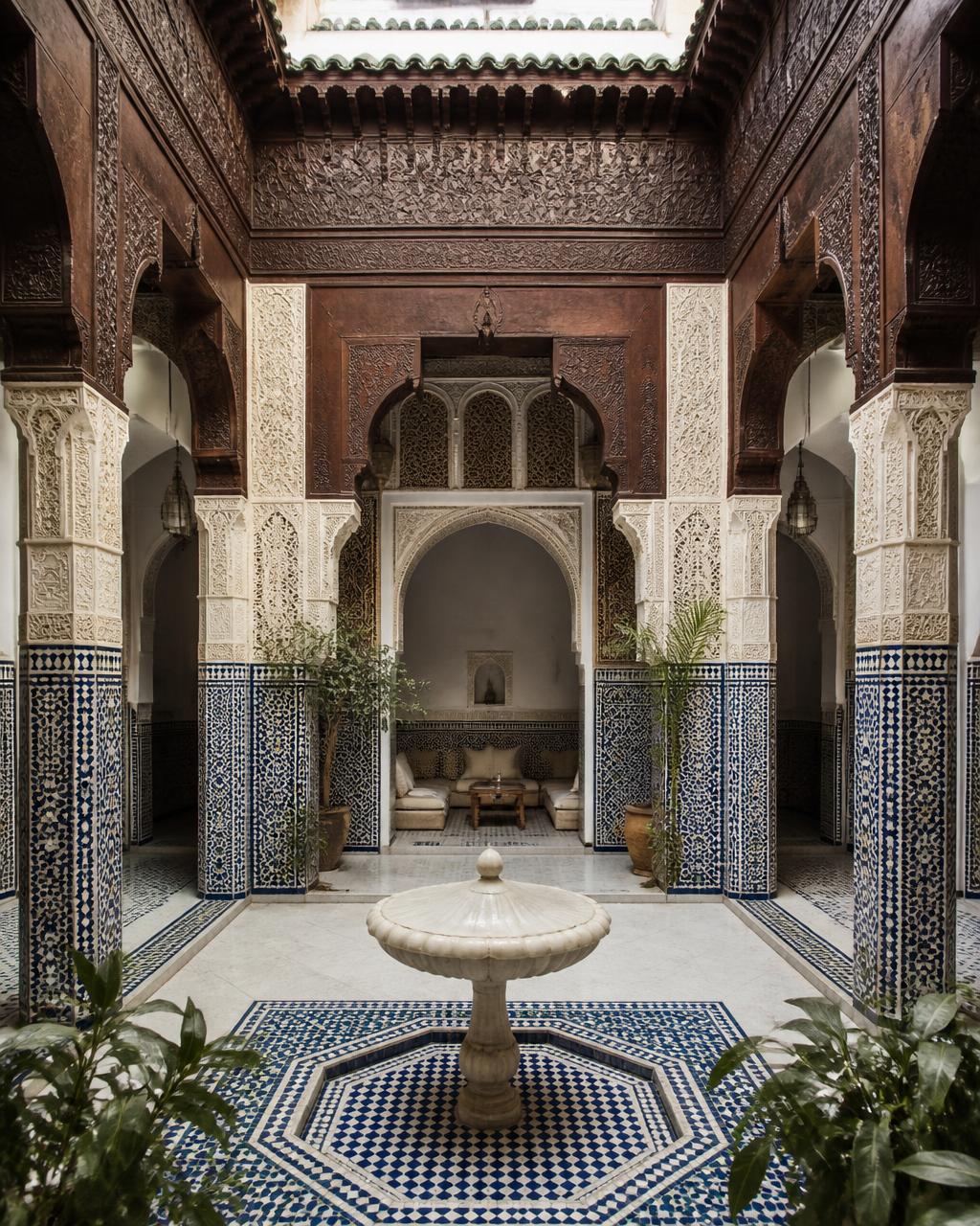 Patio central d'un riad avec zellige bleu et arcades sculptées
